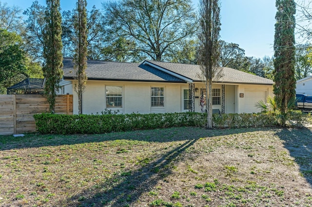 ranch-style home with brick siding, a shingled roof, fence, a garage, and a front lawn