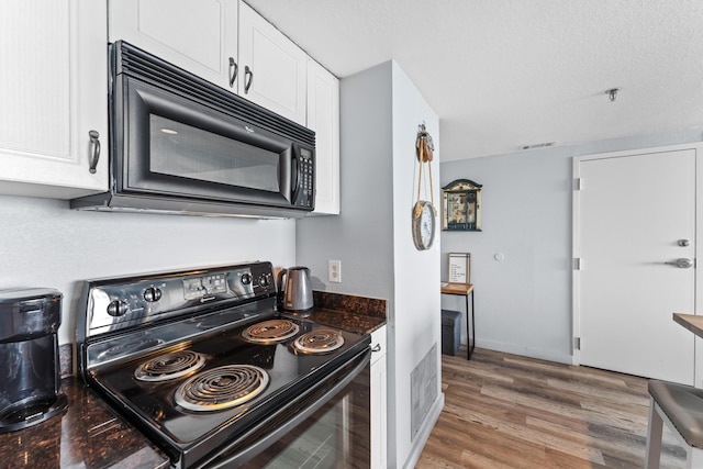 kitchen with dark countertops, visible vents, white cabinetry, wood finished floors, and black appliances