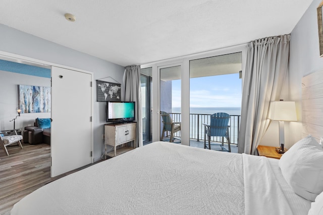 bedroom featuring access to exterior, floor to ceiling windows, and wood finished floors