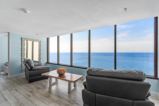 living area with a textured ceiling, light wood finished floors, and a water view