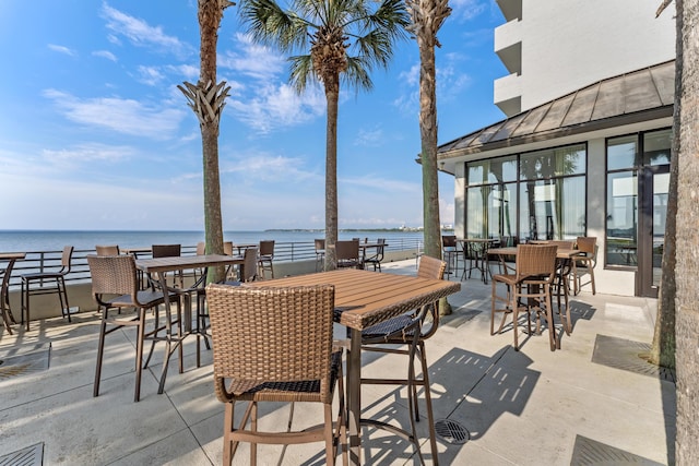 view of patio / terrace featuring outdoor dining area, a water view, and visible vents