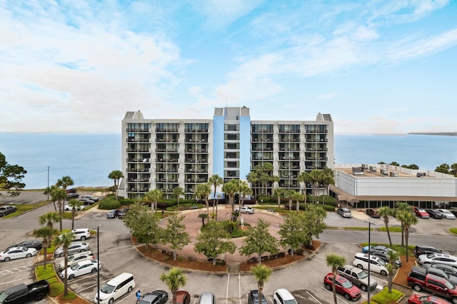 view of building exterior featuring uncovered parking and a water view