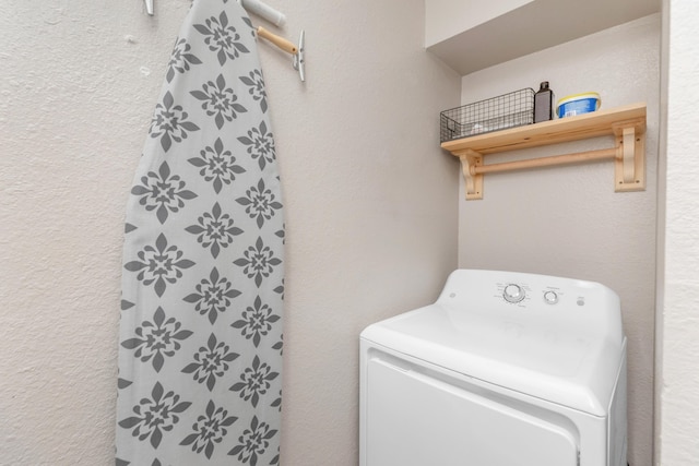 clothes washing area featuring a textured wall, laundry area, and washer / clothes dryer