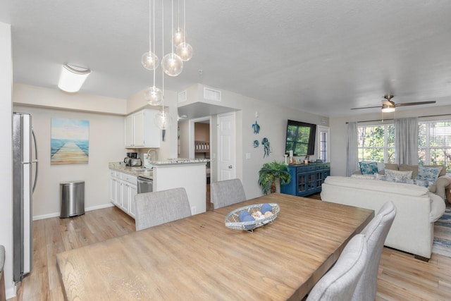 dining space featuring baseboards, visible vents, light wood-style flooring, and a ceiling fan