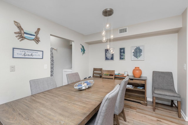 dining space with light wood-style flooring and visible vents