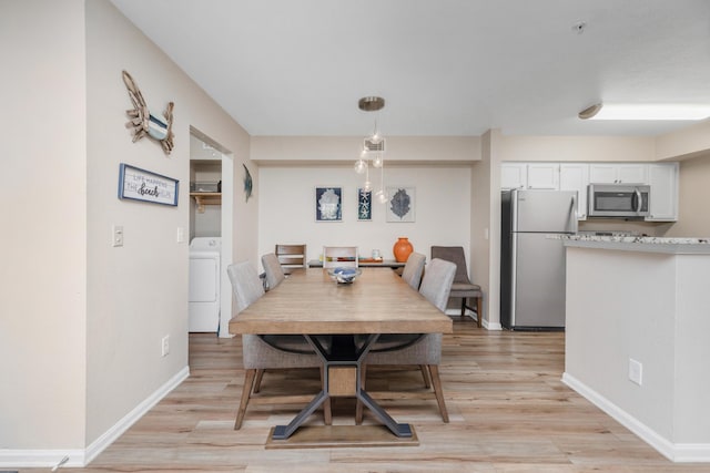 dining space featuring light wood-type flooring, washer / dryer, and baseboards