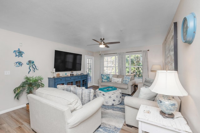 living room with light wood-style floors, baseboards, and a ceiling fan