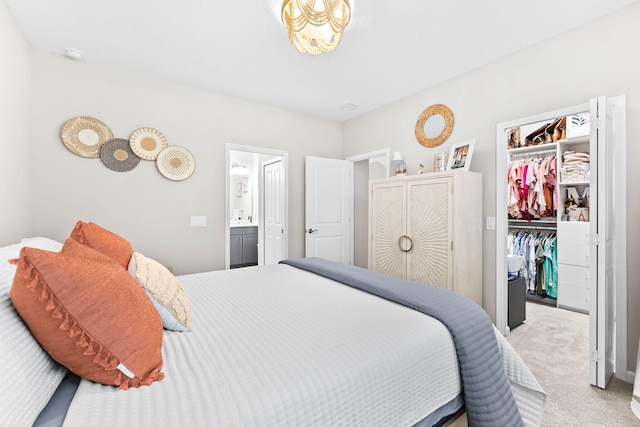 bedroom with light carpet, ensuite bath, a walk in closet, and a closet