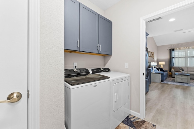 washroom with cabinet space, visible vents, washer and clothes dryer, baseboards, and light wood-style flooring