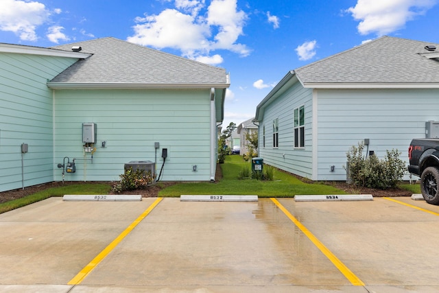 view of home's exterior with a shingled roof and uncovered parking