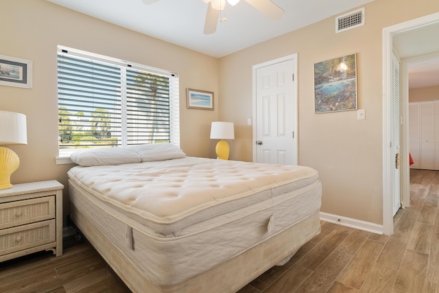 bedroom featuring a ceiling fan, visible vents, baseboards, and wood finished floors