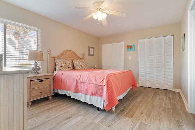 bedroom featuring light wood-type flooring, ceiling fan, baseboards, and two closets