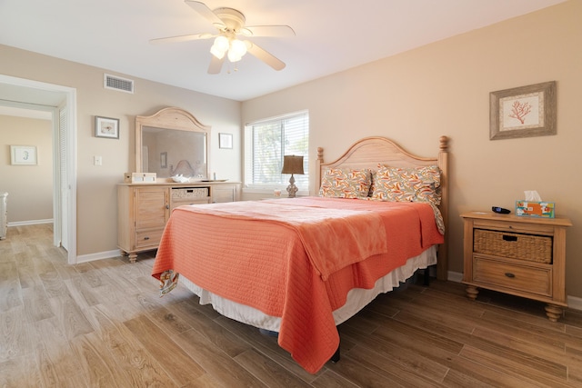 bedroom with light wood-style floors, visible vents, ceiling fan, and baseboards