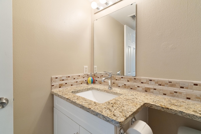 half bathroom with visible vents, vanity, and decorative backsplash