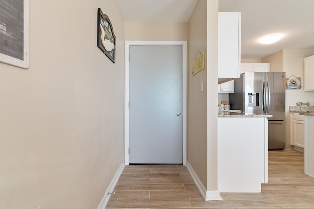 corridor featuring light wood-style flooring and baseboards