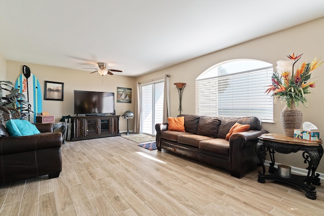 living area with light wood-type flooring, plenty of natural light, baseboards, and ceiling fan