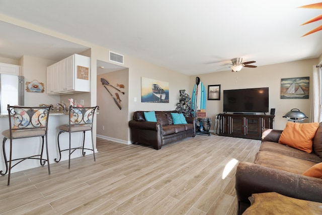 living area with light wood-style floors, visible vents, ceiling fan, and baseboards