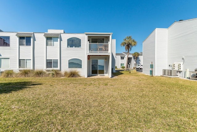 rear view of house featuring a yard, central AC unit, and a balcony