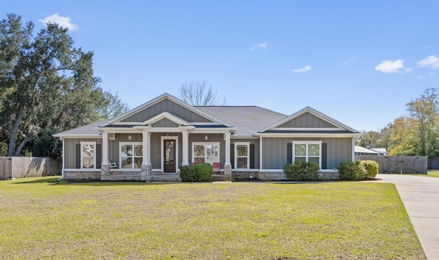 view of front facade featuring brick siding, board and batten siding, a front lawn, and fence