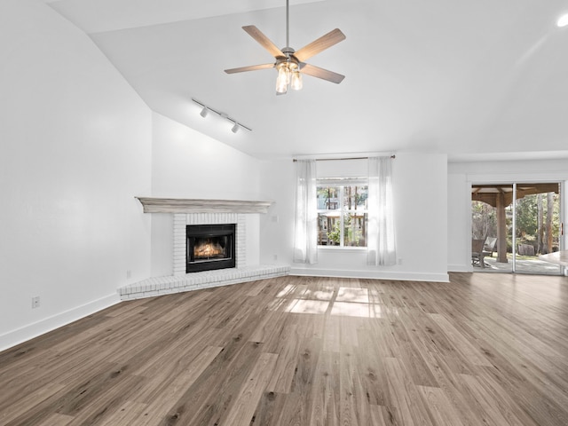 unfurnished living room featuring plenty of natural light, a fireplace, ceiling fan, and wood finished floors