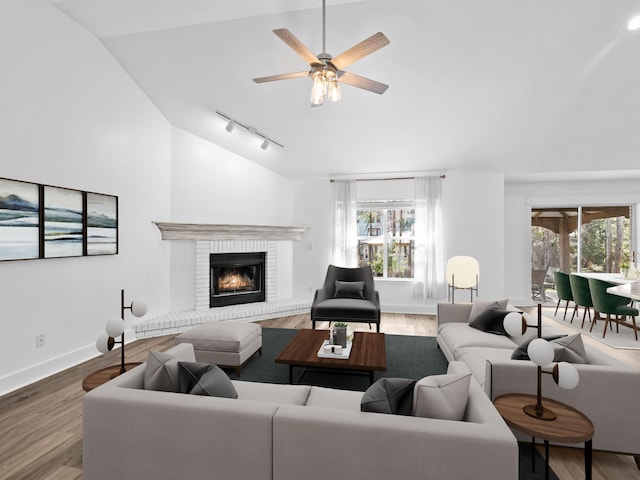 living area with vaulted ceiling, a fireplace, wood finished floors, and baseboards