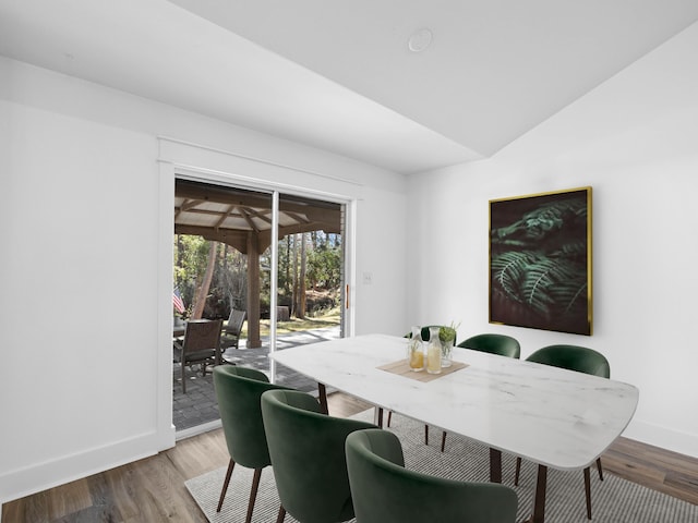 dining space featuring lofted ceiling, baseboards, and wood finished floors