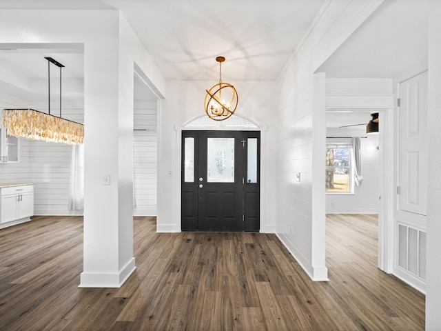 entrance foyer featuring dark wood-style floors, visible vents, baseboards, and an inviting chandelier