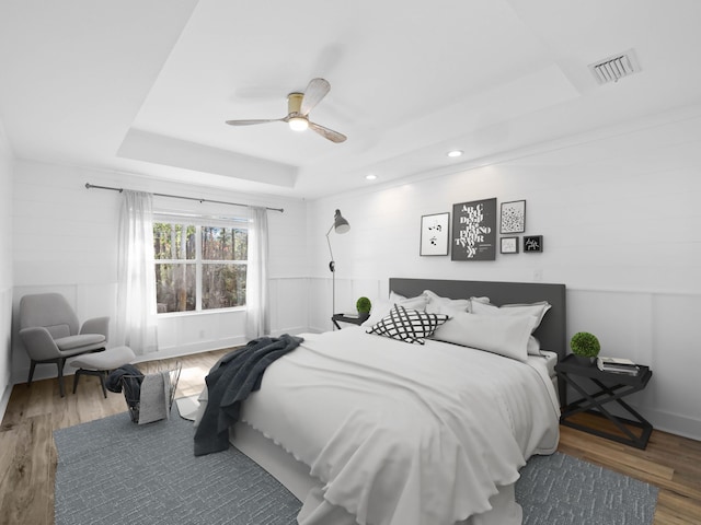 bedroom with visible vents, a raised ceiling, a ceiling fan, wood finished floors, and recessed lighting