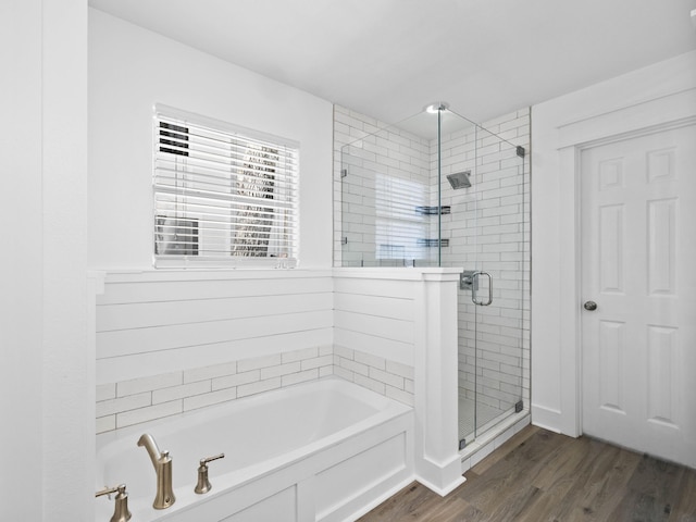 bathroom featuring wood finished floors, a garden tub, and a shower stall