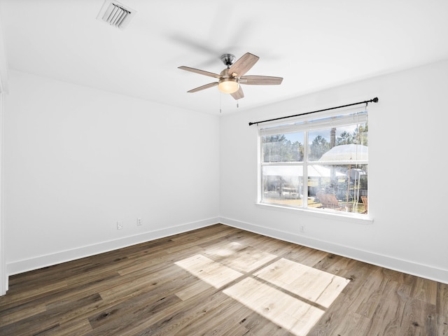 empty room featuring dark wood-type flooring, visible vents, baseboards, and a ceiling fan