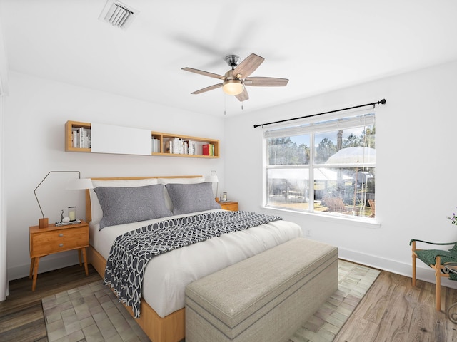 bedroom featuring visible vents, ceiling fan, baseboards, and wood finished floors