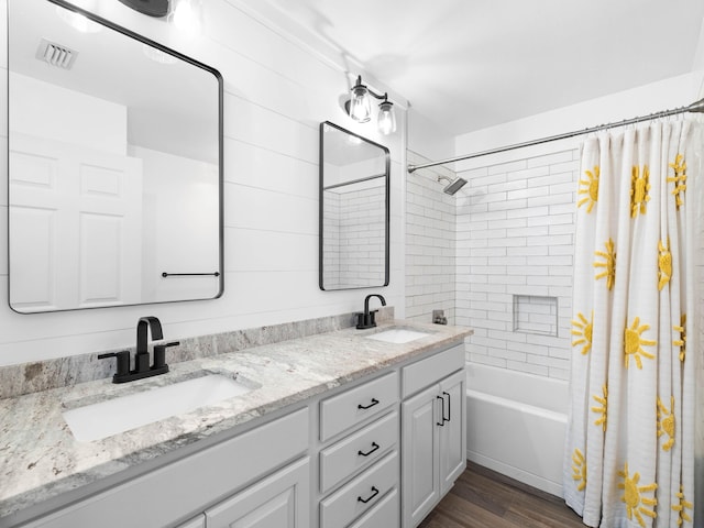 full bathroom featuring double vanity, shower / bath combination with curtain, wood finished floors, and a sink