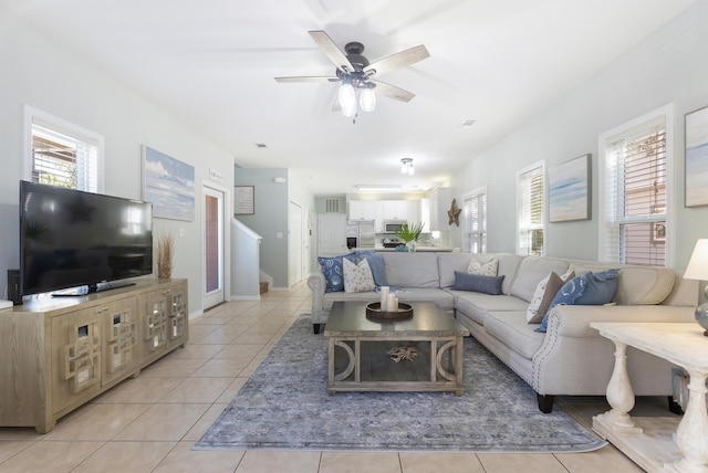 living room featuring a healthy amount of sunlight, light tile patterned floors, ceiling fan, and stairs