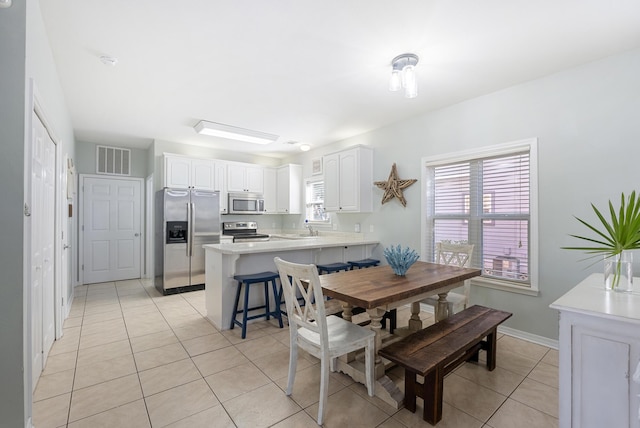 dining area with light tile patterned floors, baseboards, and visible vents