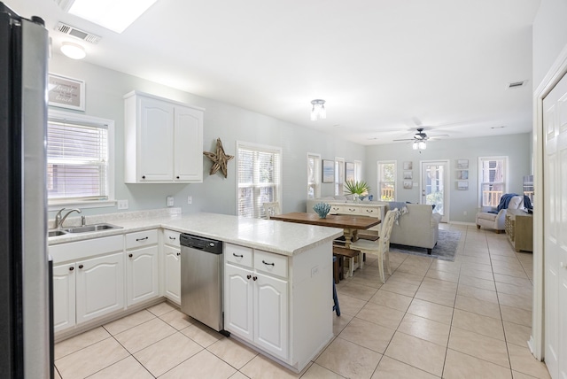 kitchen with stainless steel appliances, a peninsula, white cabinets, open floor plan, and light countertops