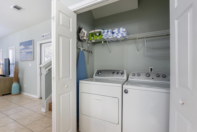 clothes washing area featuring light tile patterned floors, laundry area, visible vents, baseboards, and independent washer and dryer