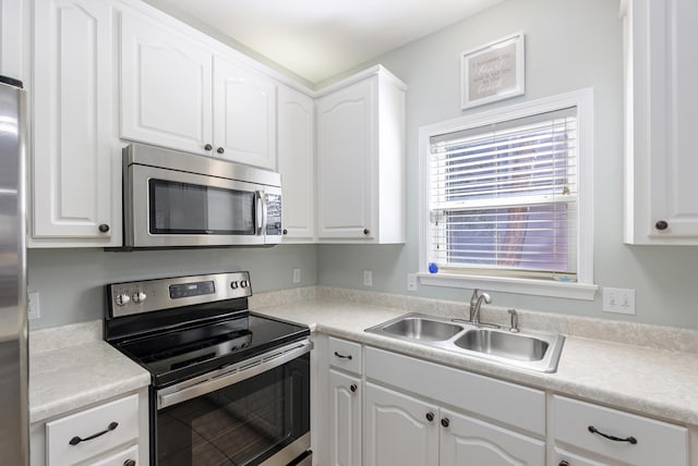 kitchen featuring white cabinetry, stainless steel appliances, a sink, and light countertops