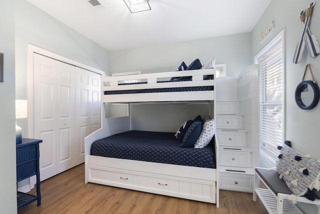 bedroom with a closet, visible vents, and wood finished floors