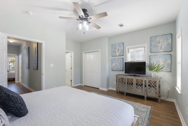 bedroom with dark wood-style floors, baseboards, visible vents, and ceiling fan