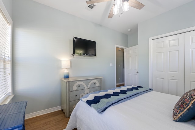 bedroom with multiple windows, baseboards, a closet, and wood finished floors