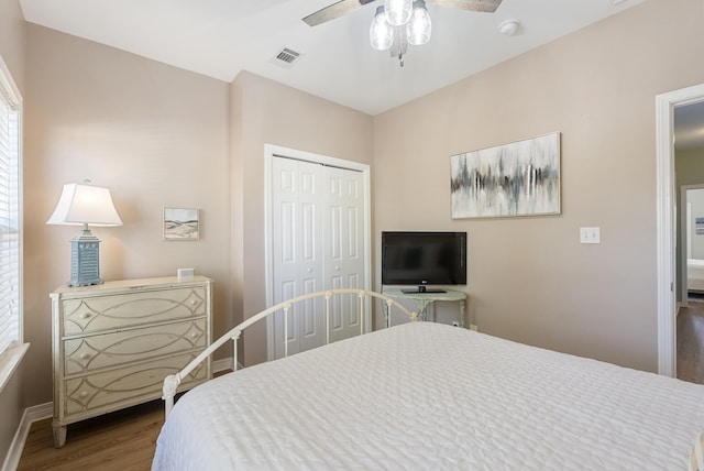 bedroom featuring a closet, visible vents, ceiling fan, wood finished floors, and baseboards