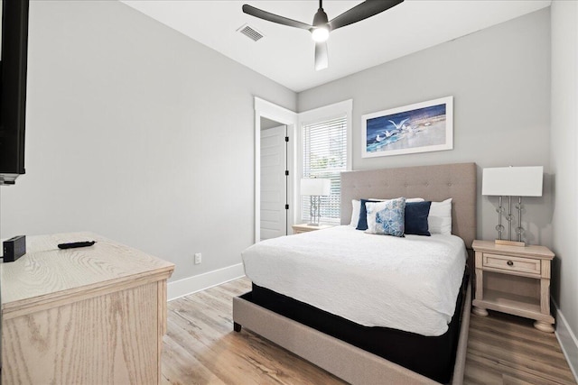 bedroom with a ceiling fan, baseboards, visible vents, and wood finished floors