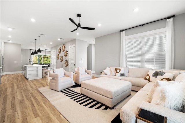 living area featuring light wood-style flooring, baseboards, ceiling fan, and recessed lighting