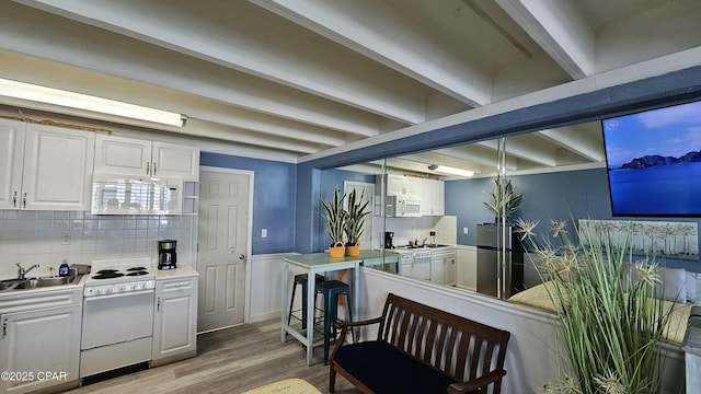 kitchen featuring white appliances, hanging light fixtures, light countertops, white cabinetry, and a sink