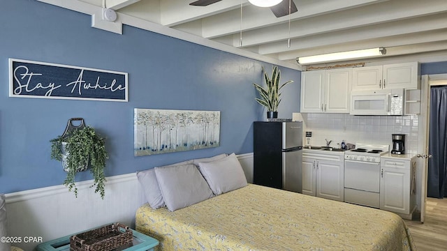 bedroom featuring beamed ceiling, a sink, freestanding refrigerator, and light wood-style floors