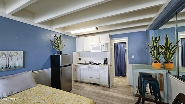 kitchen featuring white appliances, light wood-style floors, white cabinets, light countertops, and beamed ceiling