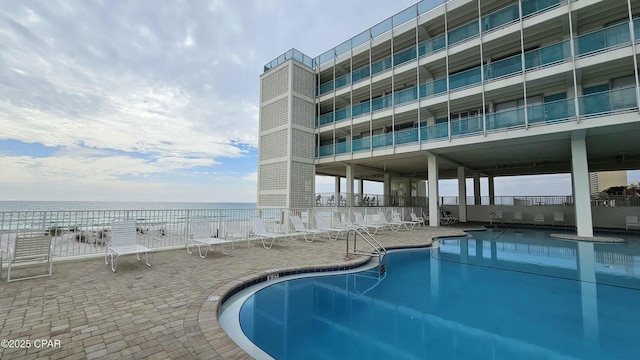 view of pool with a patio area, a water view, and fence