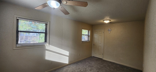 spare room with a textured ceiling, a textured wall, ceiling fan, carpet floors, and baseboards