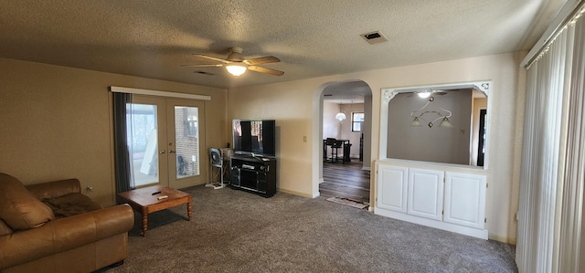 living room with visible vents, arched walkways, ceiling fan, french doors, and dark carpet