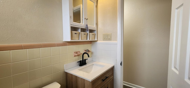 bathroom with a textured wall, tile walls, and vanity